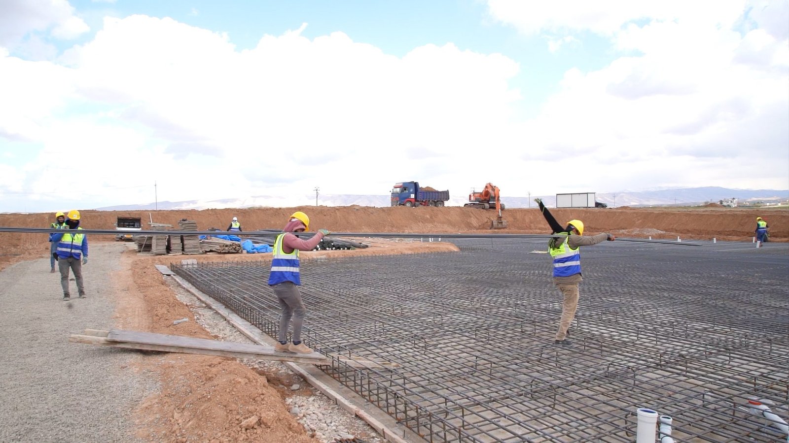 Construction workers carrying reinforcement steel on site